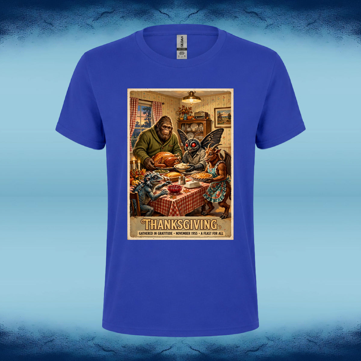 Royal blue crewneck graphic tee featuring Bigfoot, Mothman, and fellow cryptids gathered around a Thanksgiving dinner table.
