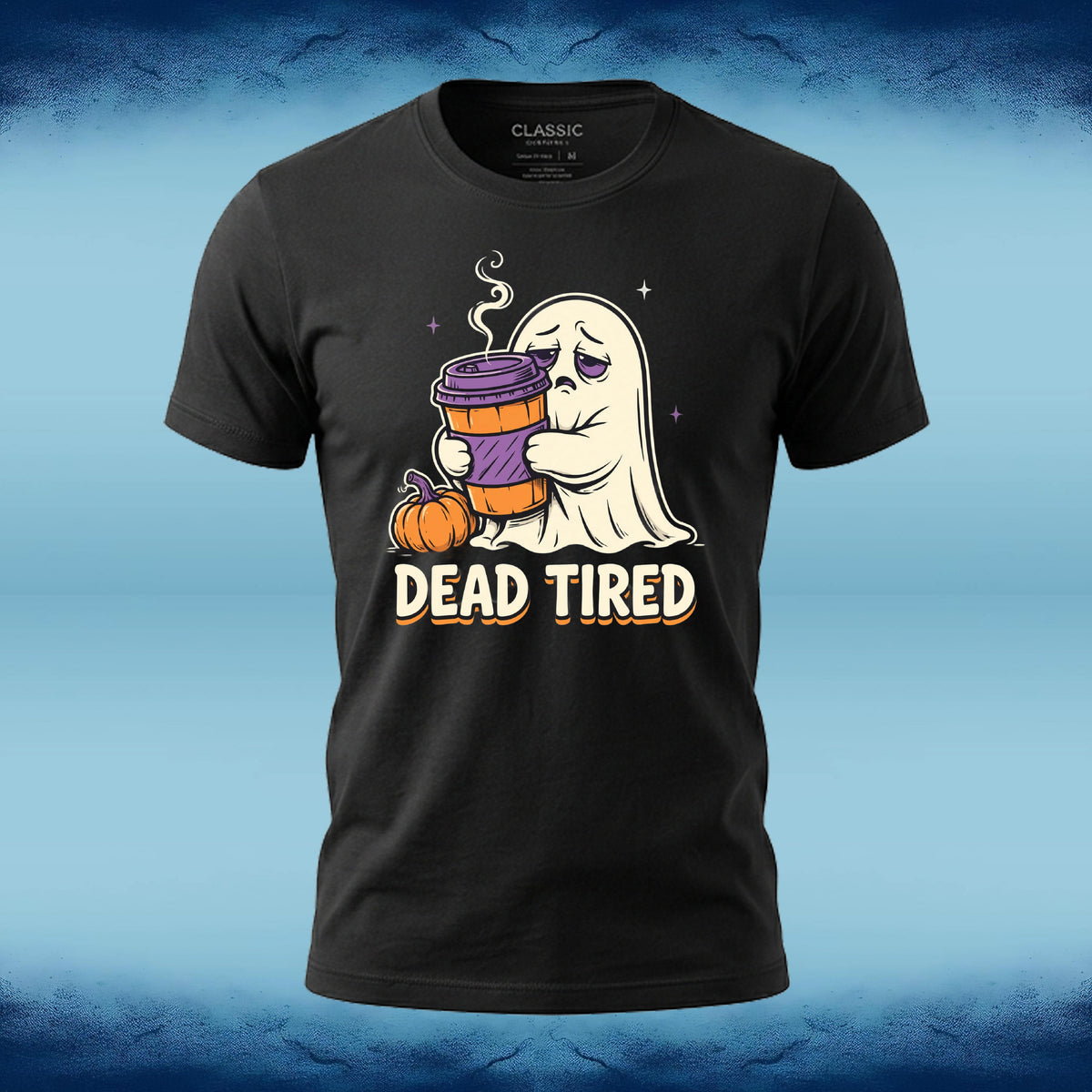 A black short-sleeve graphic t-shirt featuring a cartoon ghost holding a purple coffee cup next to a pumpkin with the text 'DEAD TIRED' underneath. The shirt is displayed on a blue textured background.