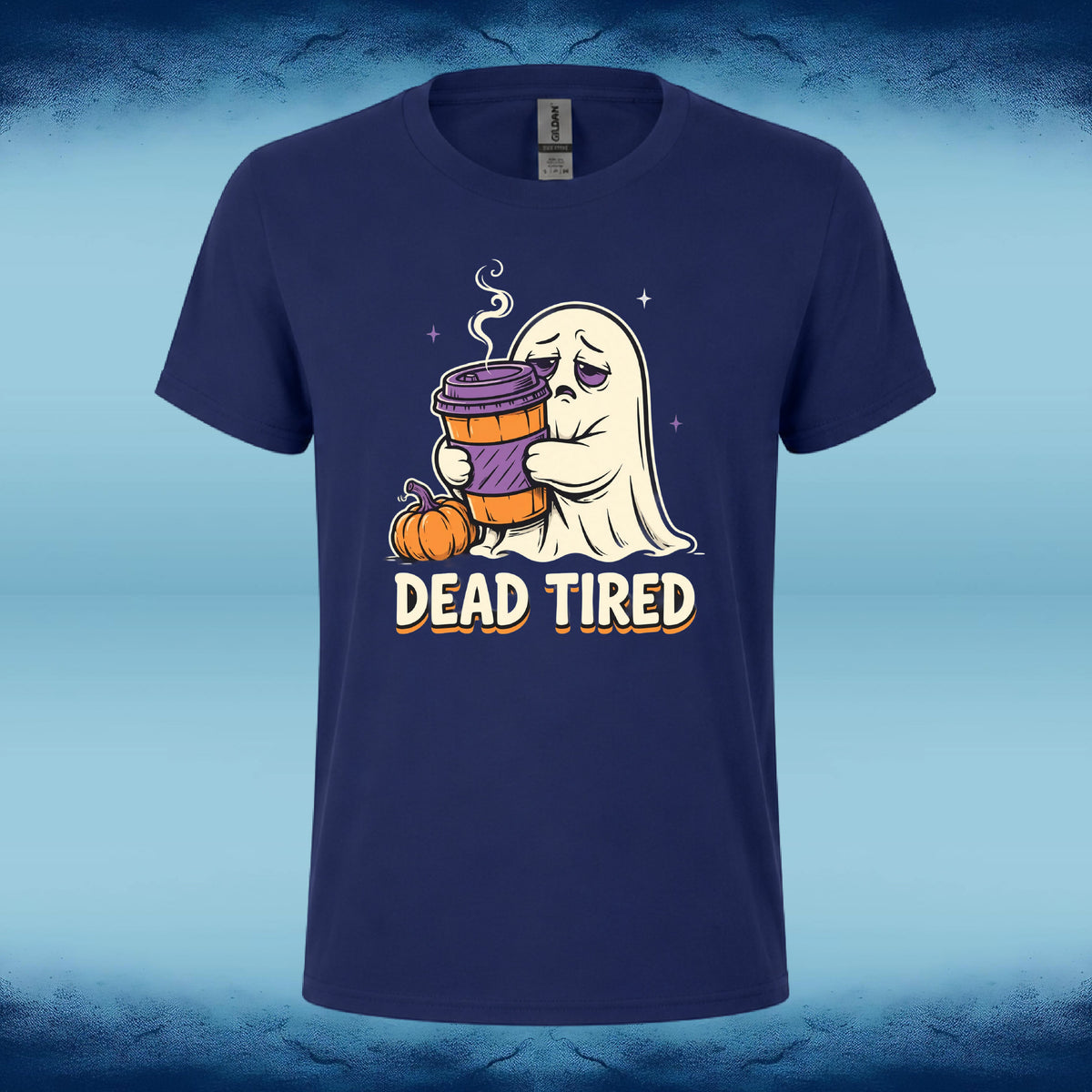 A navy blue short-sleeve t-shirt with a cartoon graphic of a ghost holding a coffee cup next to pumpkins, with the text 'DEAD TIRED' printed below. The shirt is displayed against a blue textured background.