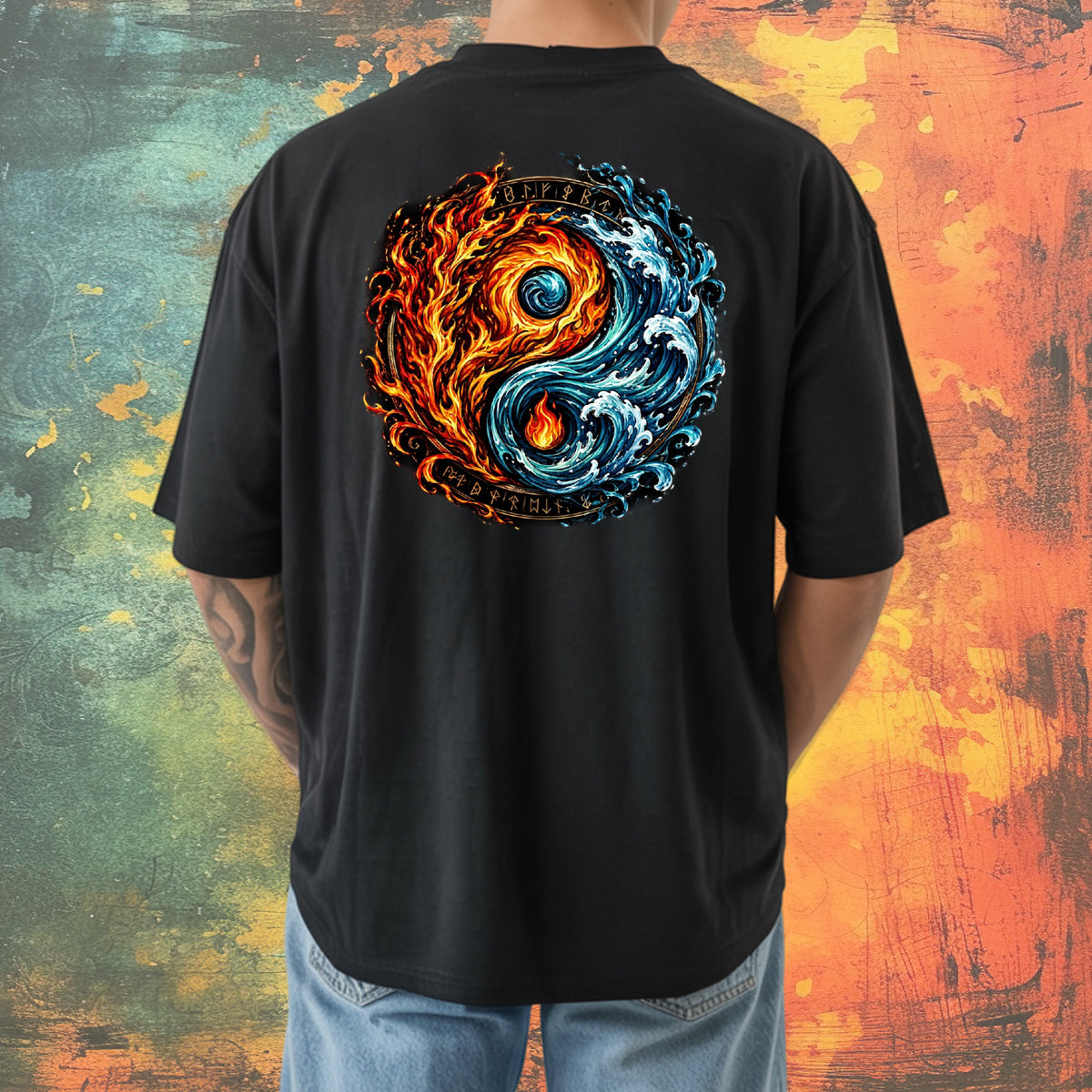 A person shown from the back wearing a black short-sleeve T-shirt with a large yin-yang style graphic on the back, featuring orange flames and blue waves with the words "Fire and Water" and "Balance." The person is also wearing light blue jeans, standing against a textured multicolor background.