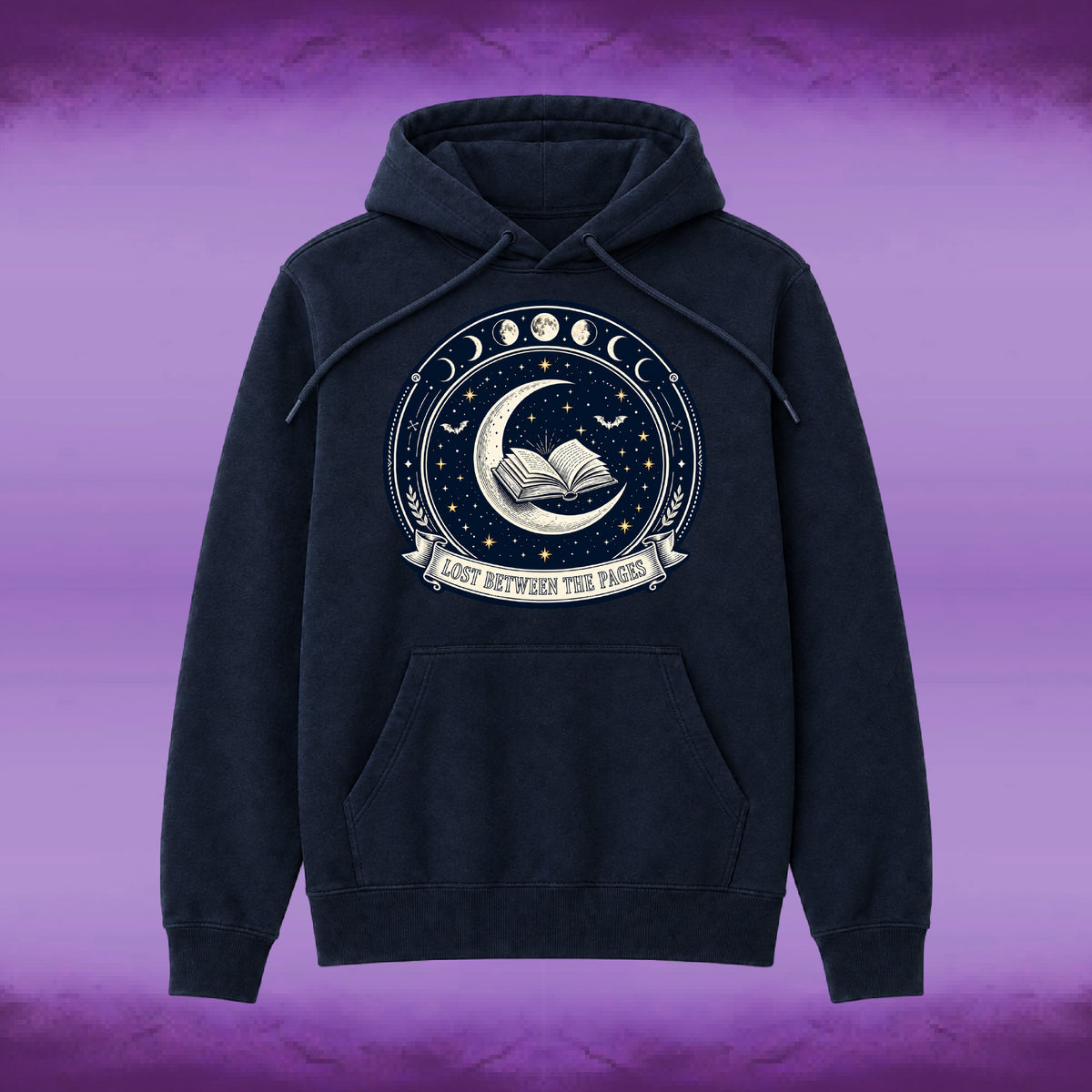 A dark navy blue hoodie with a circular celestial graphic on the chest featuring a crescent moon, open book, stars, and moon phases, with the text 'LOST BETWEEN THE PAGES' on a banner below. The hoodie is displayed against a purple gradient background.