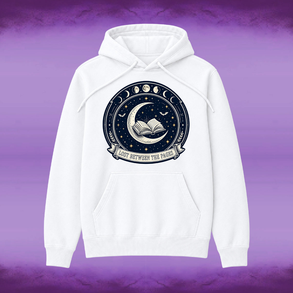 A white pullover hoodie with a circular celestial graphic on the chest featuring a crescent moon, open book, stars, and moon phases, with the text 'LOST BETWEEN THE PAGES' on a banner. The hoodie is shown against a purple textured background.