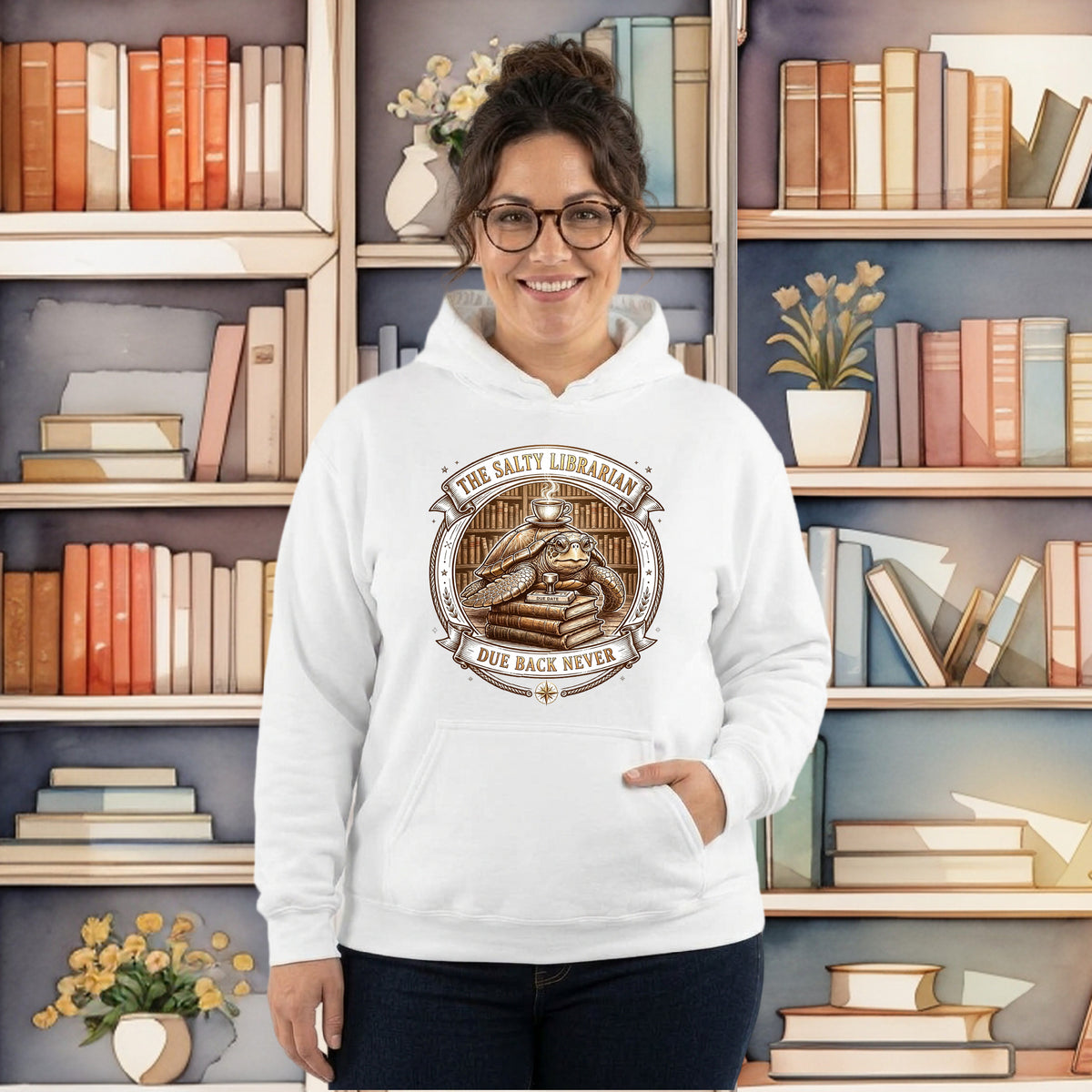 A woman wearing a white pullover hoodie with a brown graphic print that reads 'The Salty Librarian Due Back Never' stands in front of a bookshelf background.