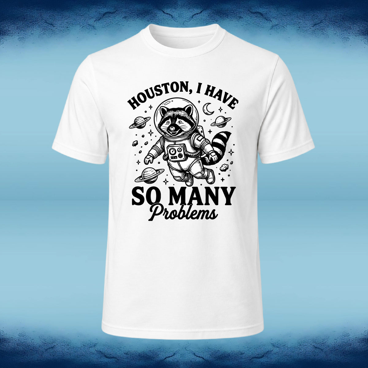 A white short-sleeve crewneck t-shirt with a black graphic print of a raccoon astronaut and the text 'HOUSTON, I HAVE SO MANY Problems', displayed against a blue gradient background.