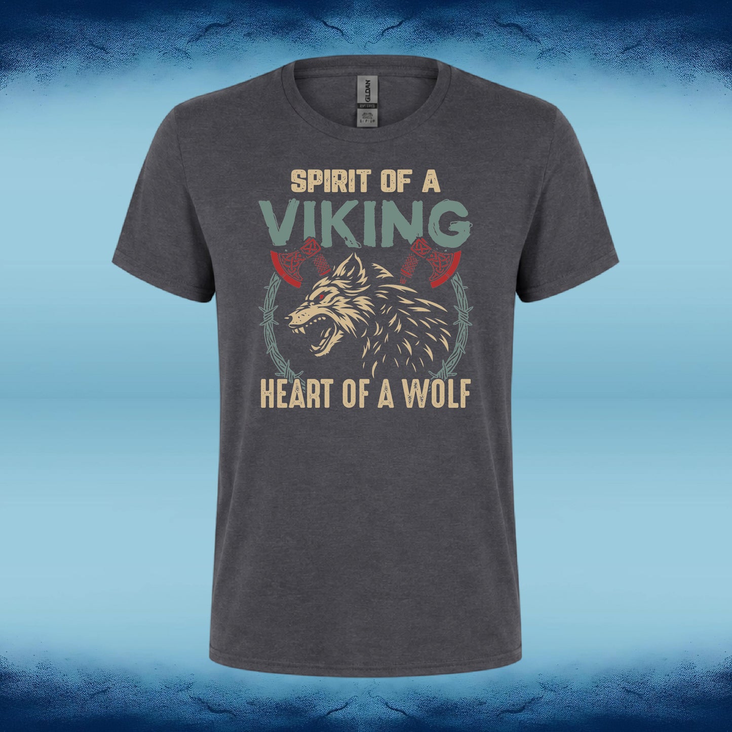 A dark heather gray t-shirt featuring a graphic print of a snarling wolf with two red axes, surrounded by the text 'SPIRIT OF A VIKING' and 'HEART OF A WOLF' in beige and light green lettering. The t-shirt is displayed against a blue textured background.
